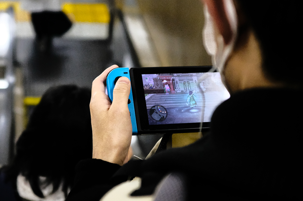 Japanese_man_playing_phone_game Man playing a nintendo switch